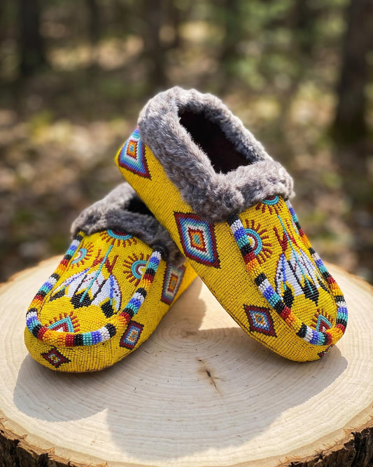 Hand-beaded golden yellow moccasins with a faux-fur cuff and a thunderbird medallion