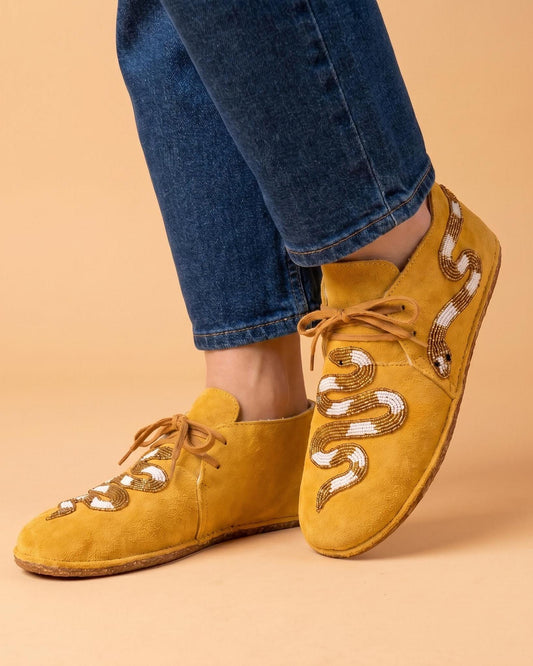 Hand-beaded golden mustard moccasins with a cream and gold coiled snake motif down the vamp