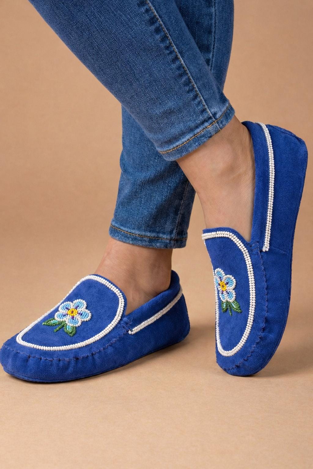 Hand-beaded royal blue suede moccasins with a blue and white flower and green leaves