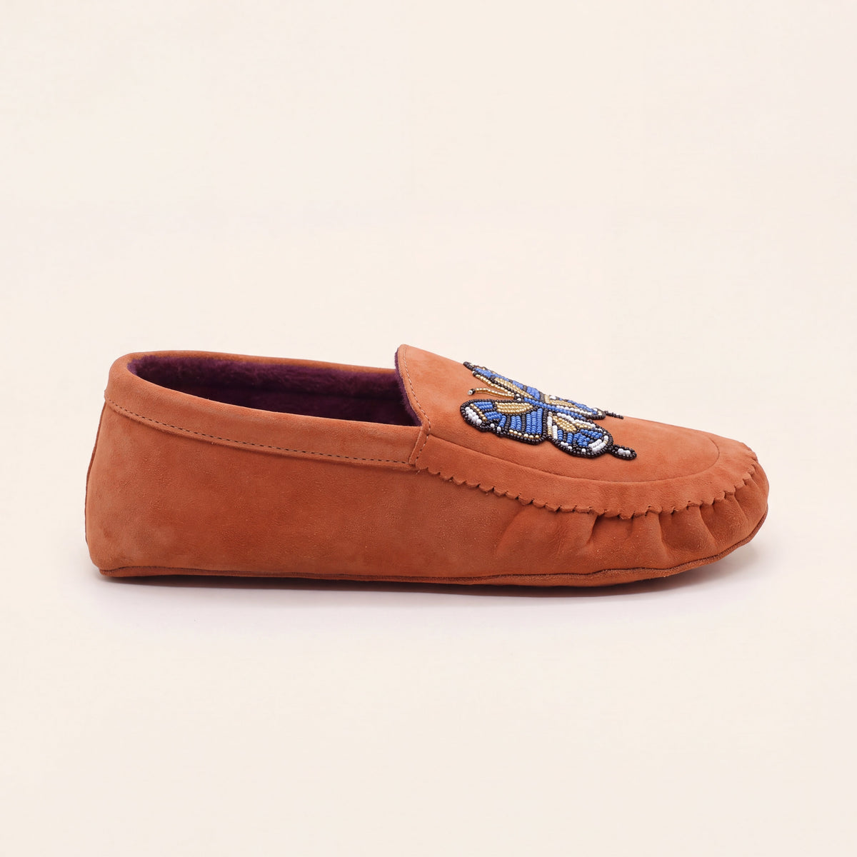 Side profile of flat coral suede slip-on moccasin with blue butterfly applique