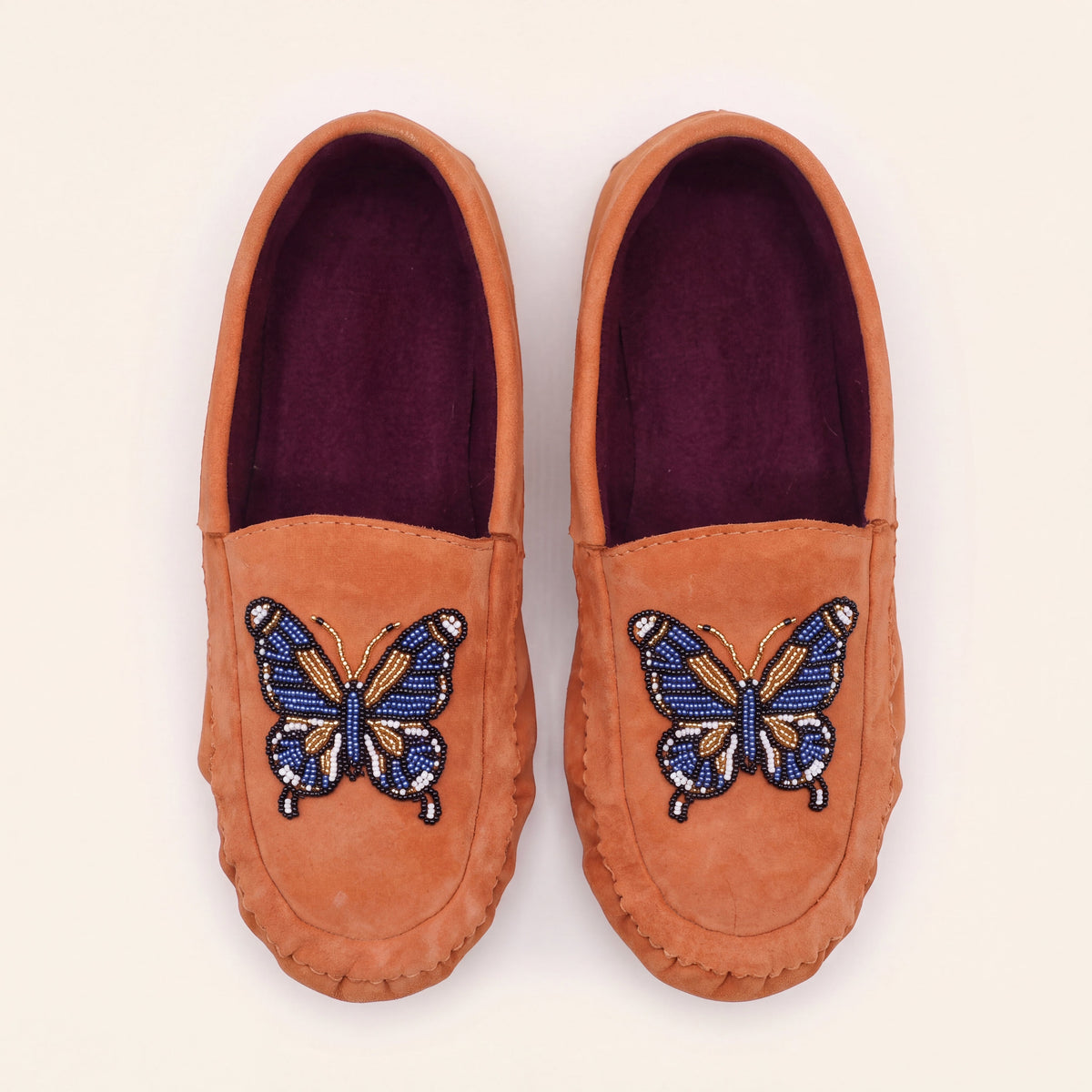 Top view of coral suede butterfly moccasins showing rich plum fabric lining