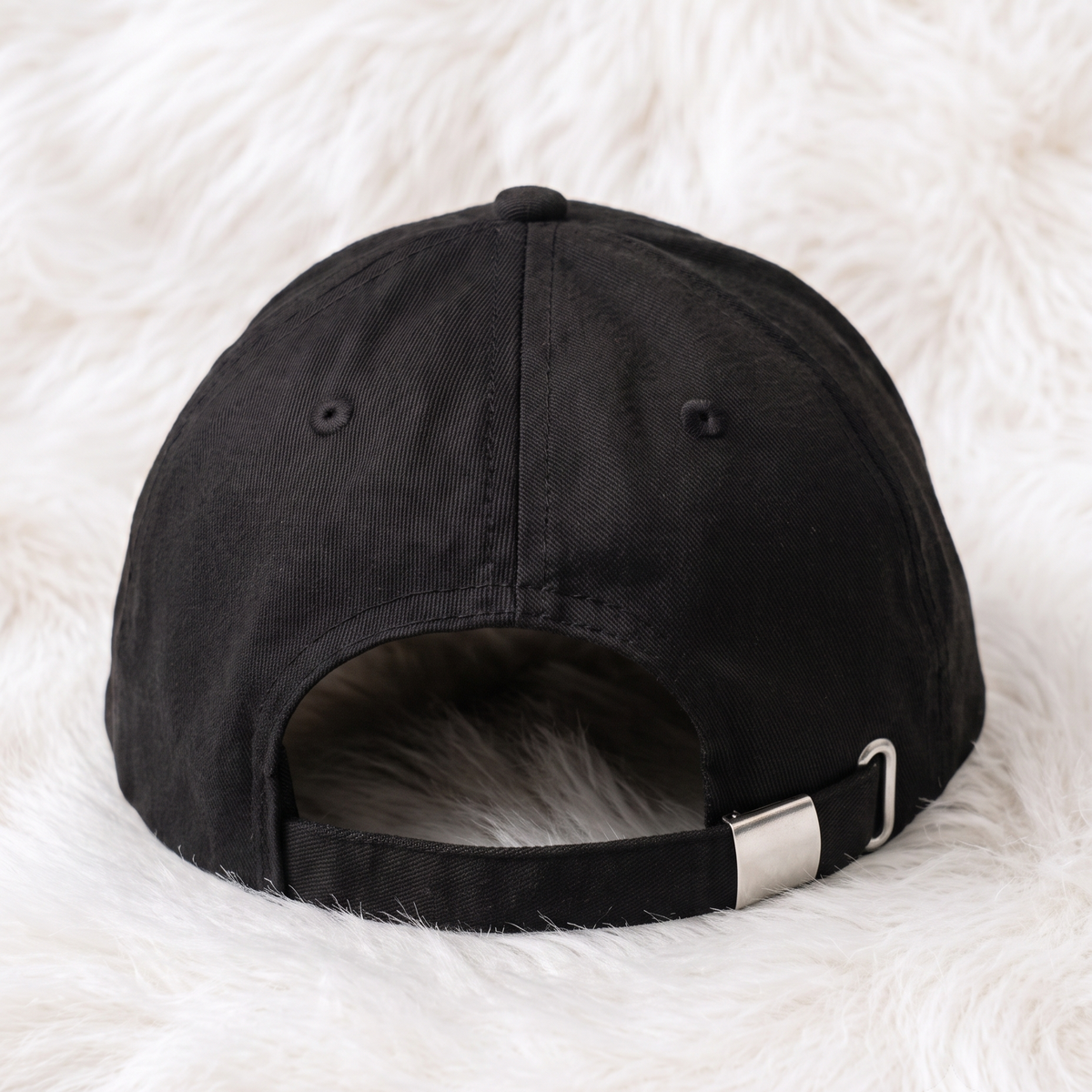 Back view of black adjustable baseball cap with metal buckle