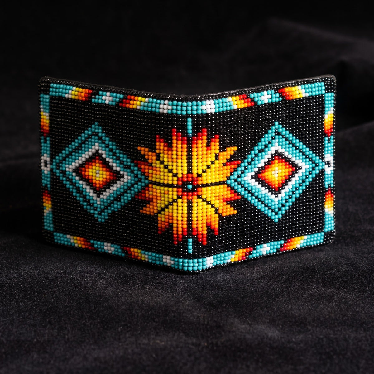 Black hand-beaded leather bifold wallet with turquoise diamond motifs and a large orange yellow sunburst center design
