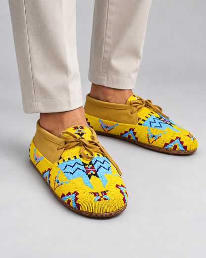 Man wearing yellow hand-beaded moccasins in a minimal premium studio setting